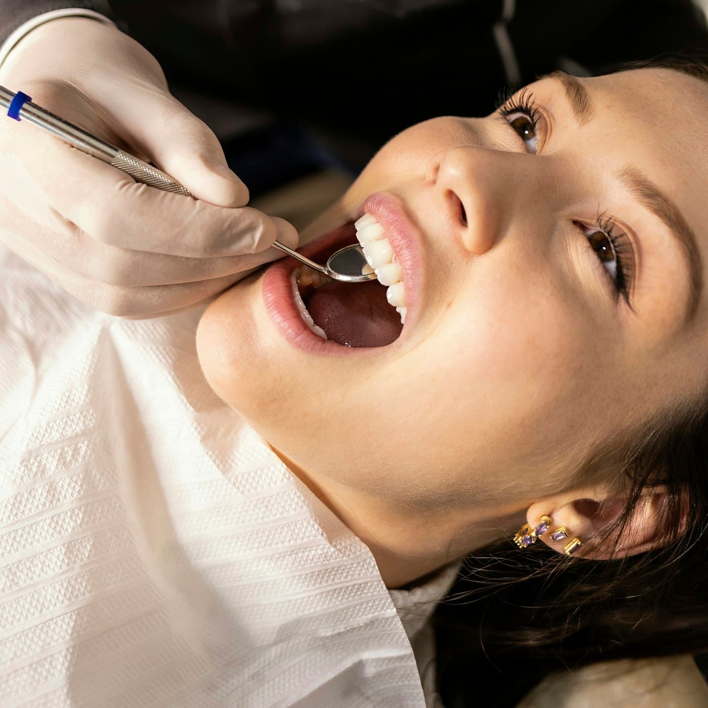 Paciente en el sillón dental recibiendo una revisión bucal con espejo intraoral